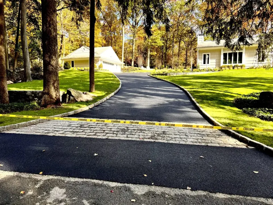 New asphalt driveway with a Belgian block apron in front of a Hudson Valley home
