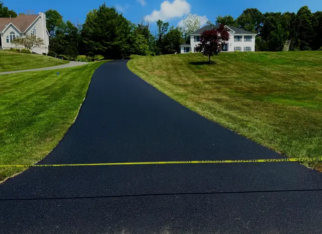Long new asphalt driveway leading to a house