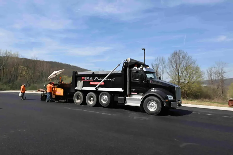 Pisa Paving dump truck and crew on a freshly paved commercial parking lot